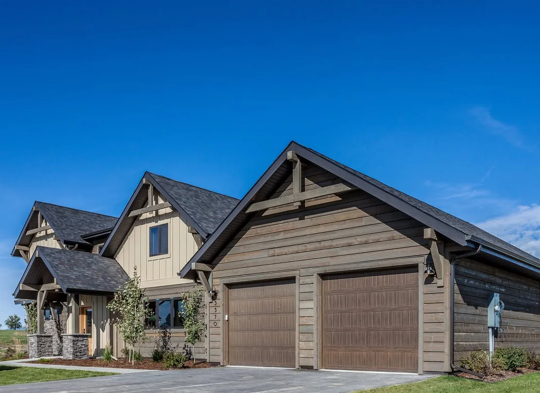A PRO Construction custom garage with timber gable detailing attached to a wood sided home